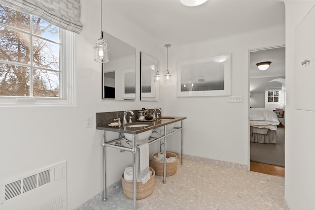 ensuite bathroom with a wealth of natural light, visible vents, baseboards, and a sink