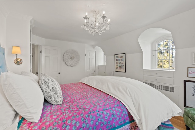 bedroom with lofted ceiling, radiator heating unit, wood finished floors, and a chandelier