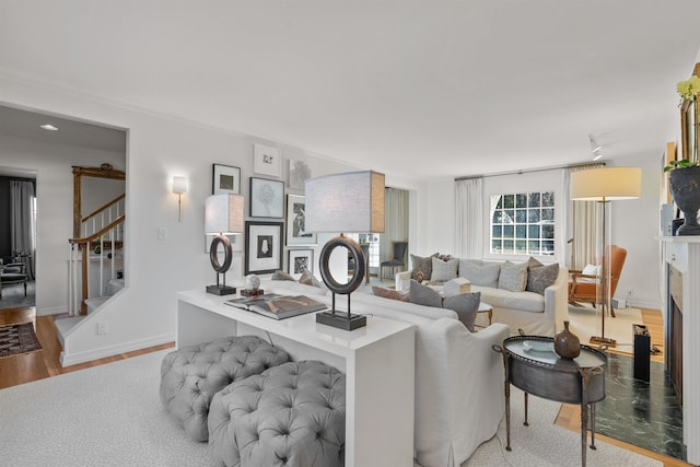 living room with stairway, baseboards, wood finished floors, and a fireplace