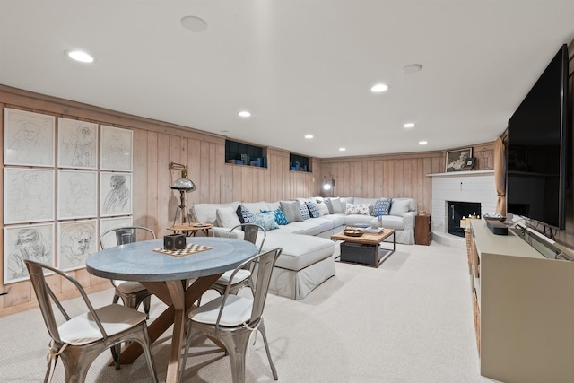 living room featuring a fireplace, wooden walls, recessed lighting, and light colored carpet