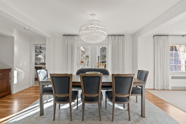 dining area featuring baseboards, radiator heating unit, french doors, wood finished floors, and a notable chandelier