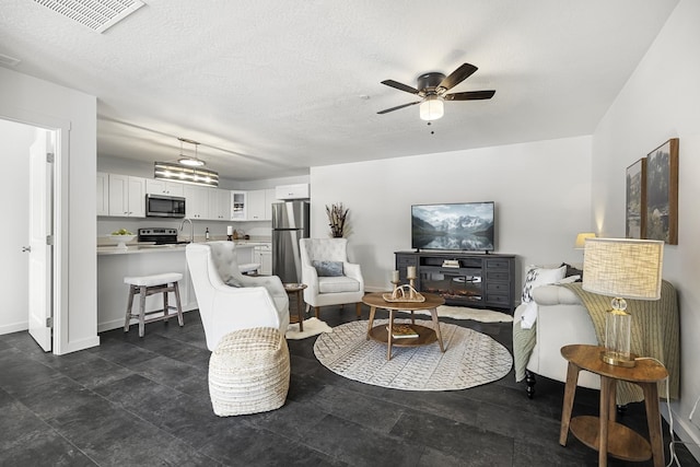 living room featuring visible vents, baseboards, a textured ceiling, and ceiling fan