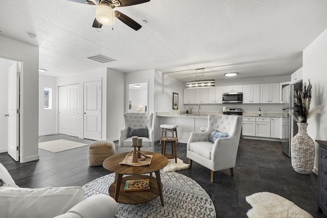 living area featuring visible vents, baseboards, dark wood finished floors, a textured ceiling, and a ceiling fan