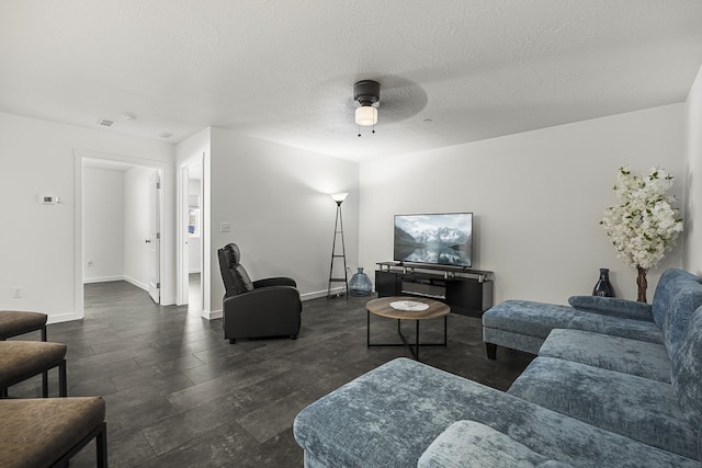 living area featuring baseboards, a textured ceiling, and ceiling fan