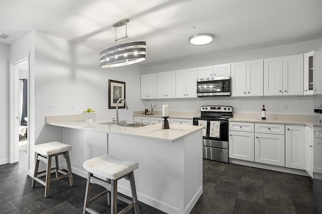 kitchen with a sink, stainless steel appliances, a peninsula, a breakfast bar area, and white cabinets