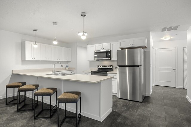 kitchen featuring visible vents, a breakfast bar, a sink, appliances with stainless steel finishes, and a peninsula