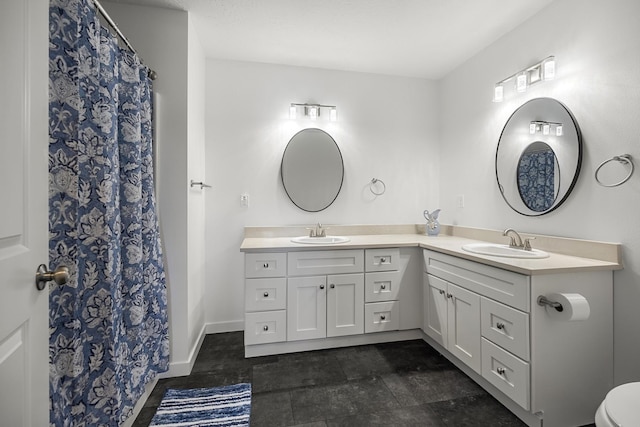 bathroom with double vanity, toilet, baseboards, and a sink