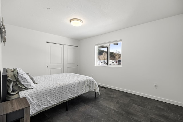 bedroom with dark wood-type flooring, visible vents, baseboards, and a closet