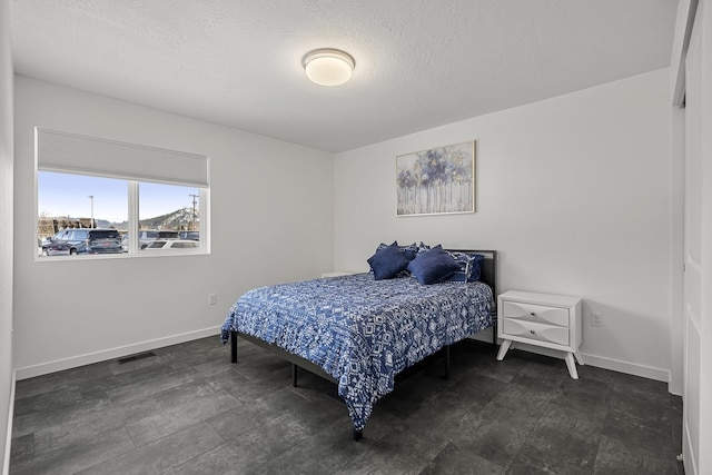 bedroom featuring visible vents, a textured ceiling, and baseboards