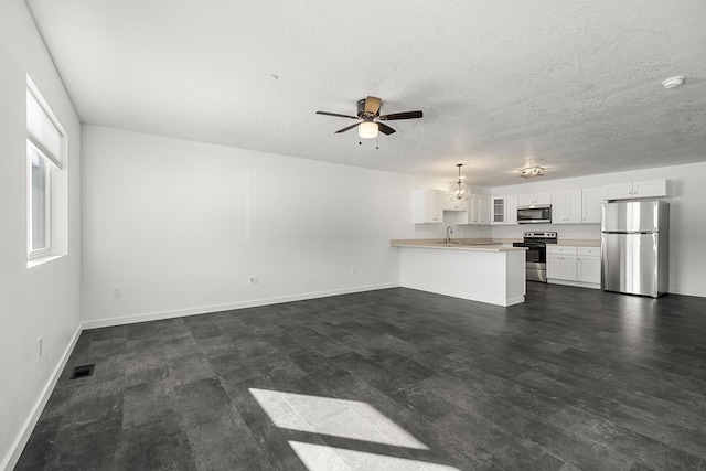 unfurnished living room featuring visible vents, dark wood-type flooring, a textured ceiling, baseboards, and ceiling fan