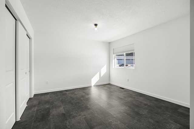 unfurnished bedroom with visible vents, baseboards, a closet, and a textured ceiling