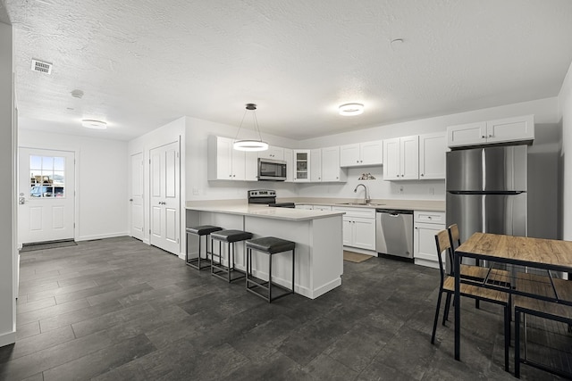 kitchen with visible vents, glass insert cabinets, appliances with stainless steel finishes, a peninsula, and a sink