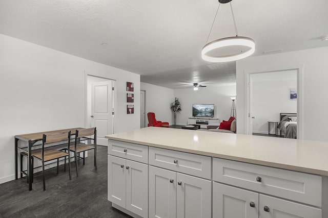 kitchen with a textured ceiling, open floor plan, hanging light fixtures, and light countertops