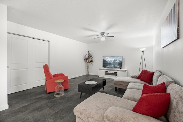 living room with a ceiling fan, baseboards, dark wood-style flooring, and a textured ceiling