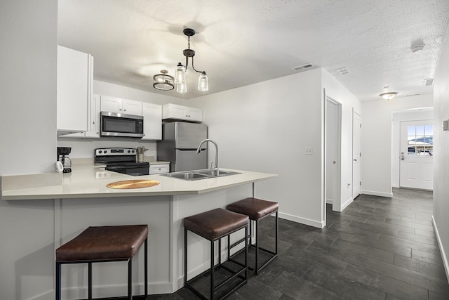 kitchen with visible vents, light countertops, a kitchen breakfast bar, stainless steel appliances, and a sink