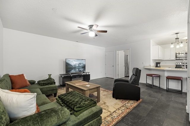 living room with ceiling fan with notable chandelier, baseboards, and a textured ceiling