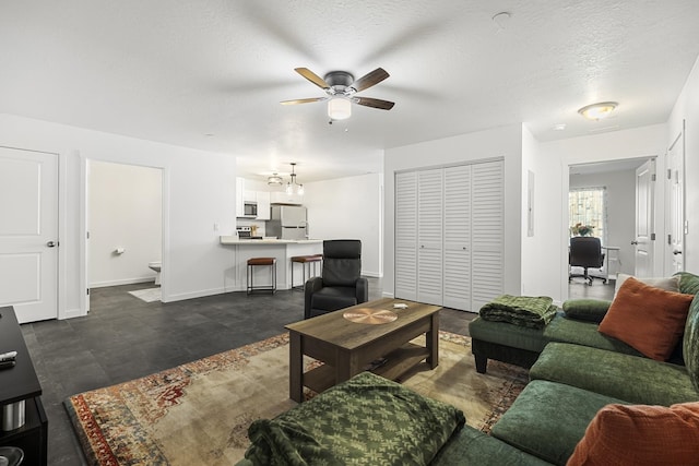 living area featuring baseboards, a textured ceiling, and a ceiling fan