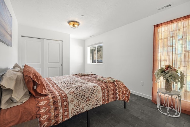 bedroom featuring baseboards, visible vents, a closet, and a textured ceiling