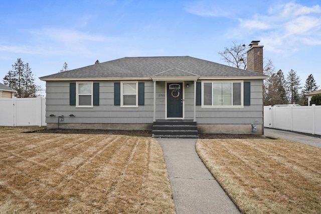 bungalow-style house featuring a chimney, a shingled roof, fence, and a gate