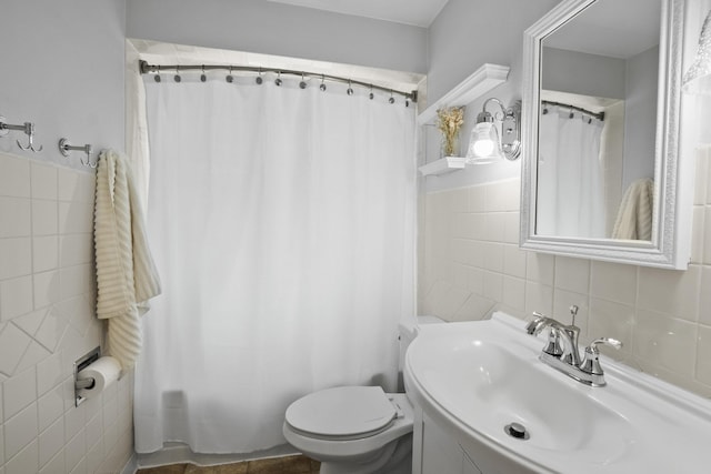 bathroom featuring tile walls, toilet, shower / tub combo with curtain, and a sink