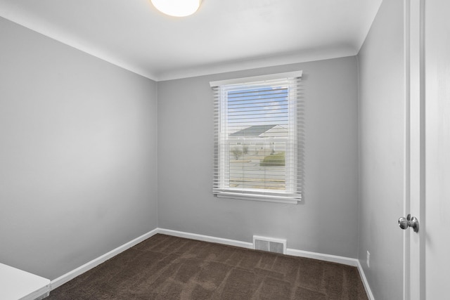 unfurnished room with visible vents, baseboards, and dark carpet