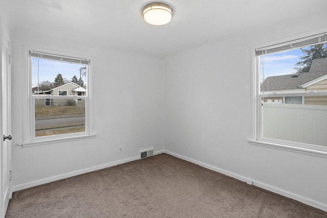 carpeted spare room featuring visible vents and baseboards