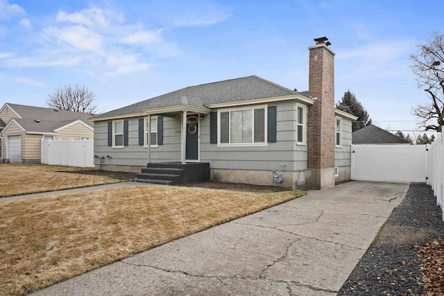 bungalow with fence, concrete driveway, roof with shingles, a chimney, and a gate