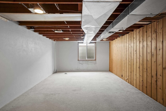 basement featuring carpet floors and wood walls