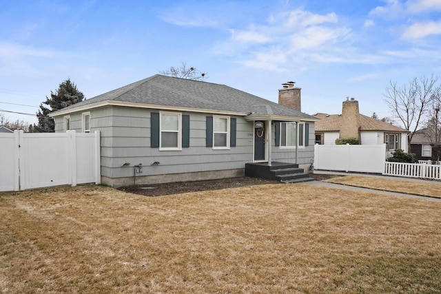 view of front of home with a front lawn, a gate, fence, roof with shingles, and a chimney