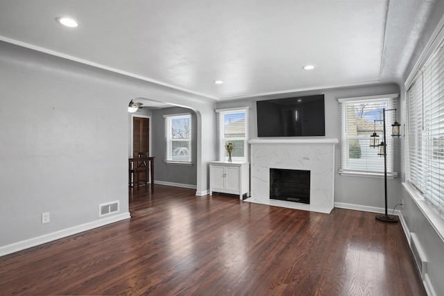 unfurnished living room with a healthy amount of sunlight, wood finished floors, visible vents, and a premium fireplace