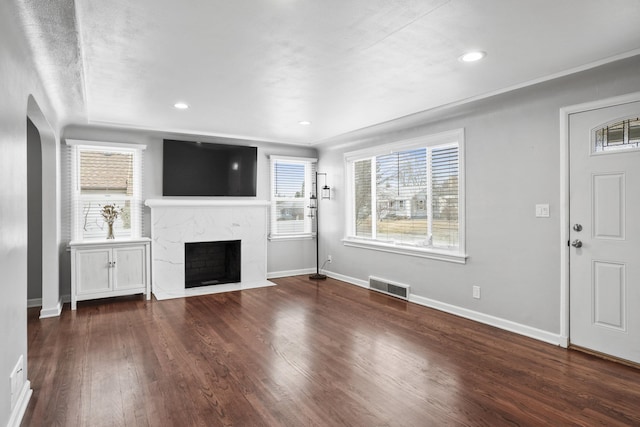 unfurnished living room with wood finished floors, a fireplace, visible vents, and a wealth of natural light