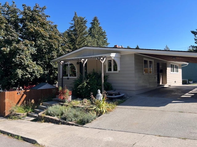 view of front facade with an attached carport, driveway, and fence