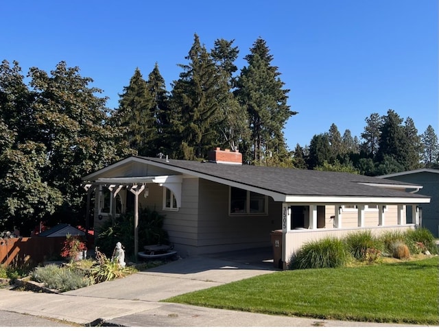 ranch-style home with a carport, concrete driveway, a chimney, and a front lawn