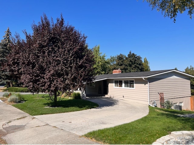 view of front of house with driveway, an attached carport, a chimney, and a front lawn