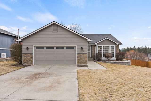 ranch-style house with a front lawn, fence, a garage, stone siding, and driveway