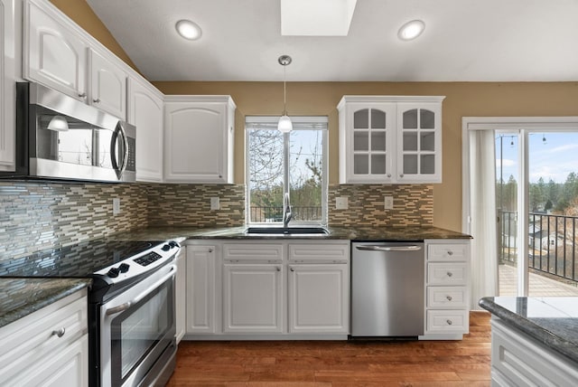 kitchen with dark wood-style floors, appliances with stainless steel finishes, white cabinetry, and glass insert cabinets