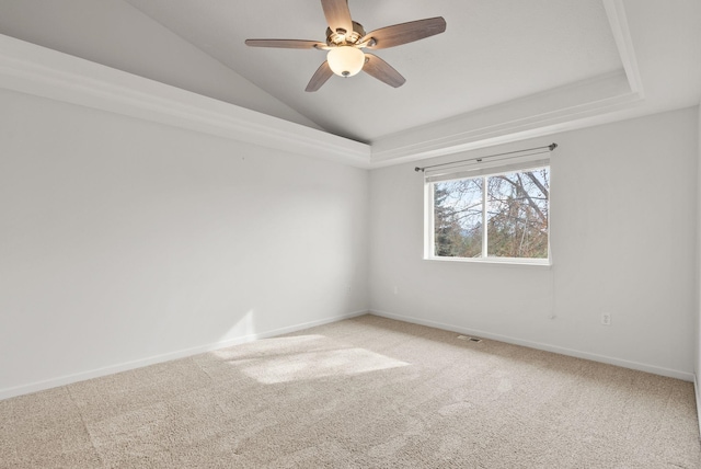 unfurnished room with visible vents, baseboards, light colored carpet, vaulted ceiling, and a raised ceiling