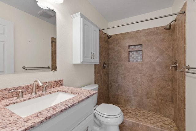 bathroom with tiled shower, toilet, and vanity