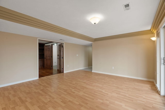 spare room with crown molding, baseboards, visible vents, and light wood finished floors