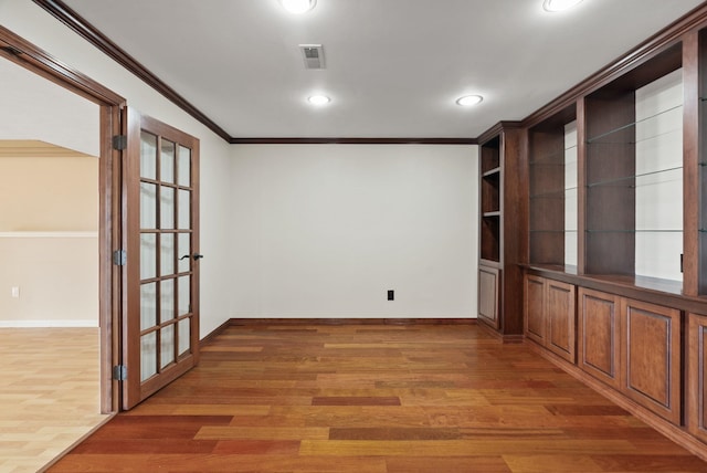 spare room with visible vents, crown molding, light wood-type flooring, and baseboards