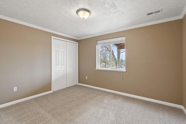 unfurnished bedroom with crown molding, baseboards, visible vents, and carpet floors