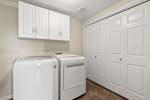 clothes washing area featuring visible vents, cabinet space, baseboards, and washer and clothes dryer