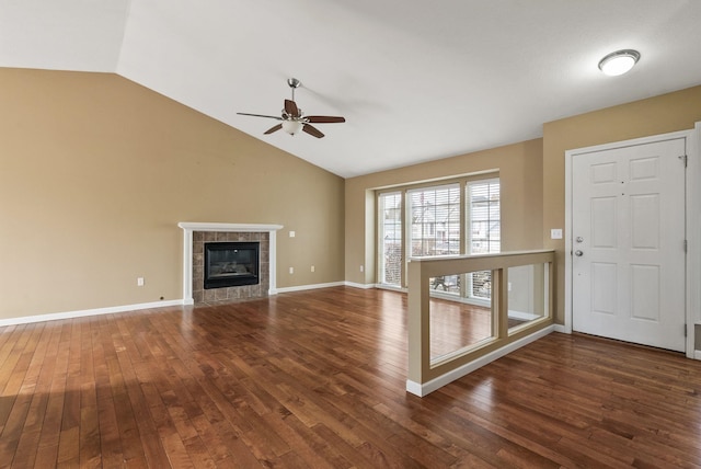 unfurnished living room with a tile fireplace, baseboards, lofted ceiling, and hardwood / wood-style floors