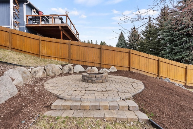 view of patio / terrace with a fire pit, a deck, and fence