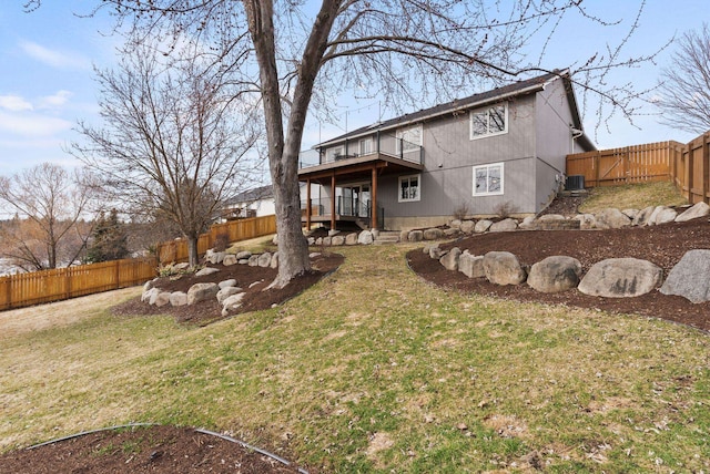 rear view of property featuring a deck, cooling unit, a fenced backyard, and a yard