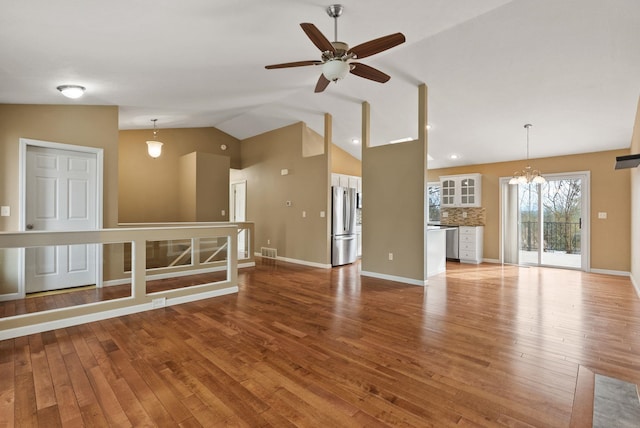 unfurnished living room featuring baseboards, lofted ceiling, light wood-style flooring, and ceiling fan with notable chandelier