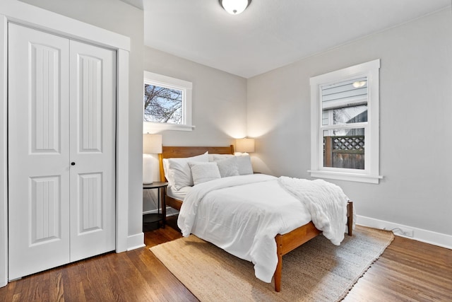 bedroom featuring baseboards, dark wood-style flooring, and a closet