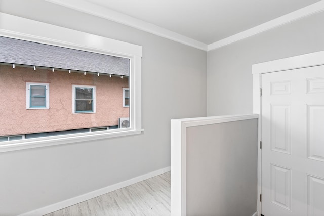 corridor featuring wood finished floors, baseboards, and ornamental molding