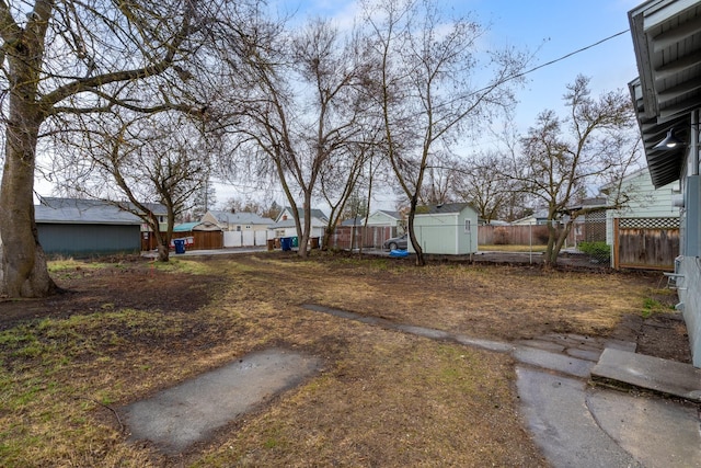 view of yard featuring an outbuilding, a storage shed, and fence