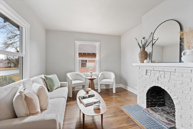 living area featuring a fireplace, baseboards, and wood finished floors